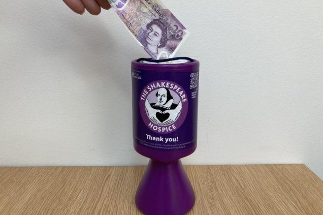 £20 note being put in to Shakespeare Hospice counter collection tin